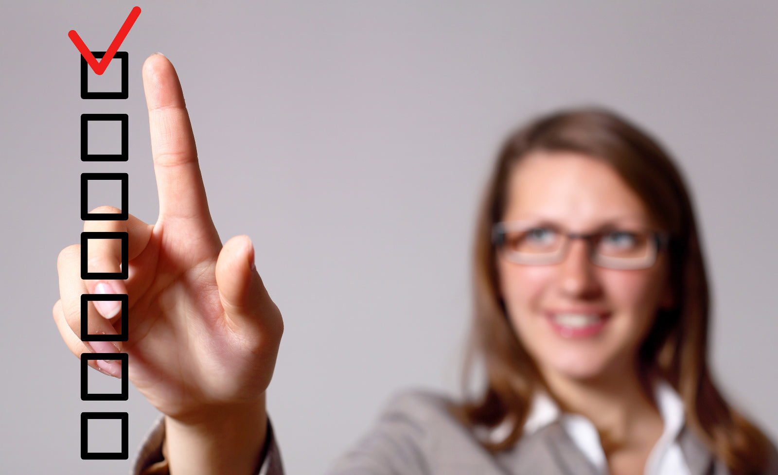 A blurred woman in the background makes a red check with her finger on a clear checklist in the foreground to illustrate checklist for bariatric surgery.