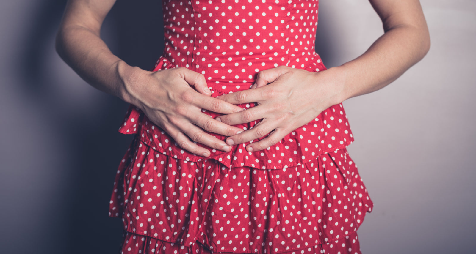 Woman in a red dress holding her stomach to help illustrate dumping syndrome symptoms and is weight loss surgery safe