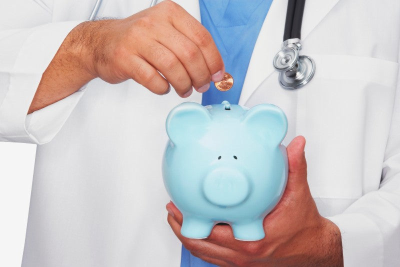 A doctor putting a coin into a blue piggy bank to help illustrate low-cost bariatric surgery